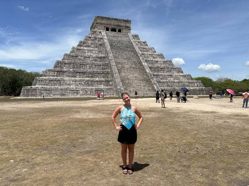 Image of a young female traveller standing in front of Chichen Itza in Mexico - KILROY