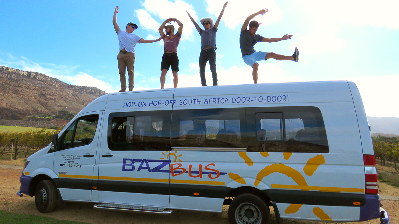 Image of a group of travellers posing on top of a Baz bus in South Africa - KILROY