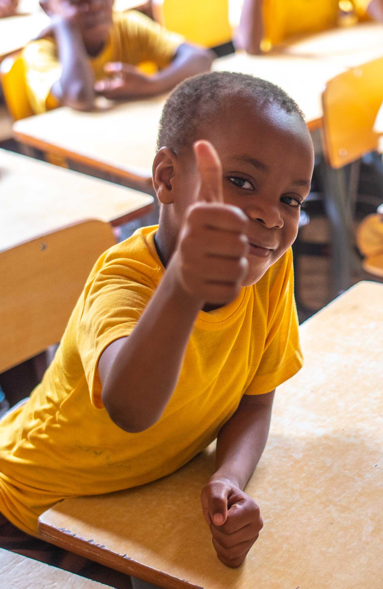 Image of a young child at a desk in Tanzania as part of a volunteer project - KILROY