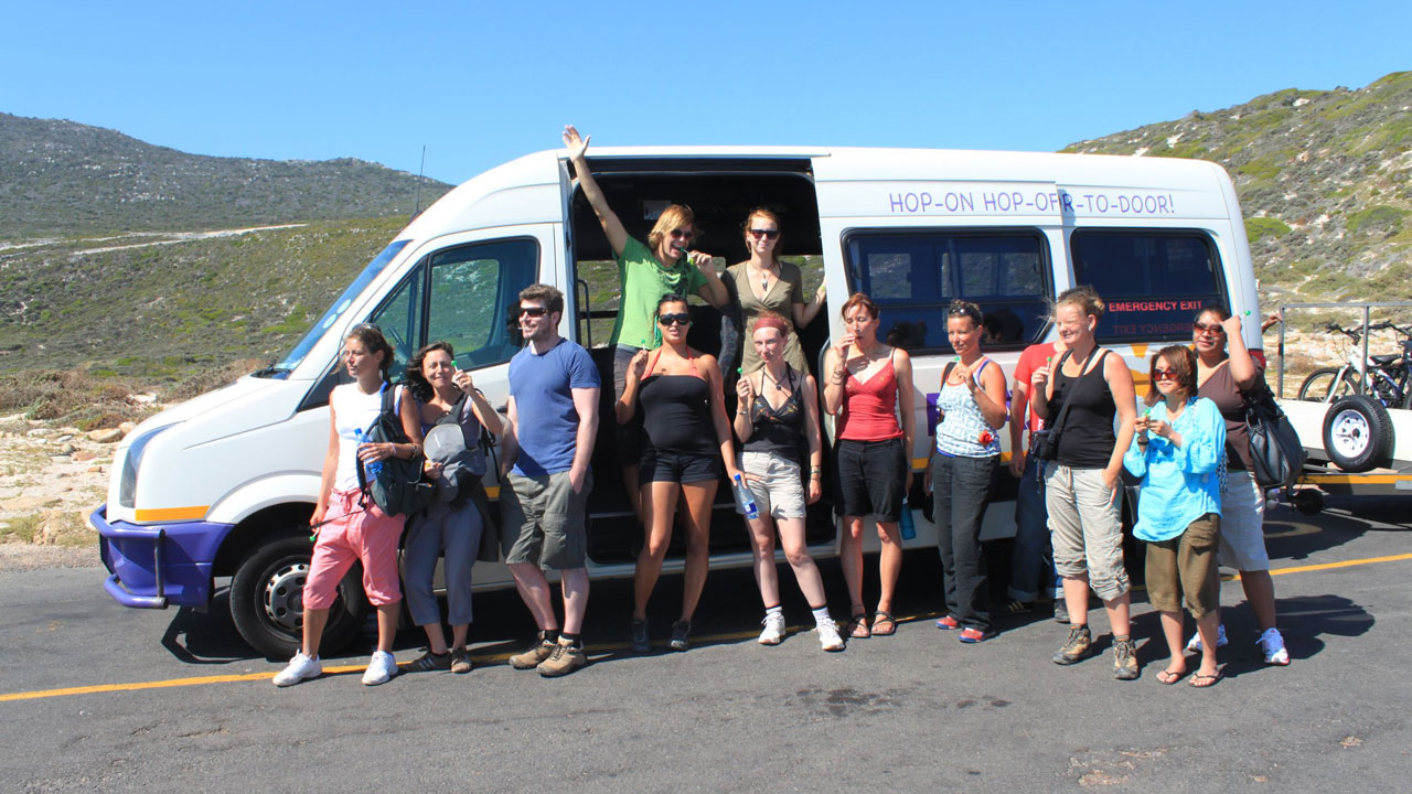 Image of a group of travellers posing outside a Baz Bus in South Africa - KILROY