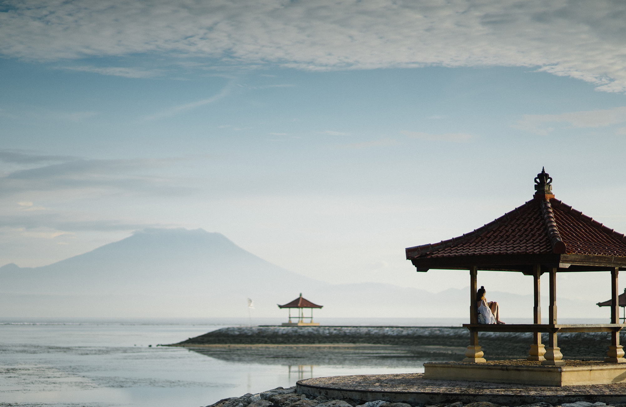 Image of a woman sitting in a pagoda overlooking a lake in Indonesia - KILROY