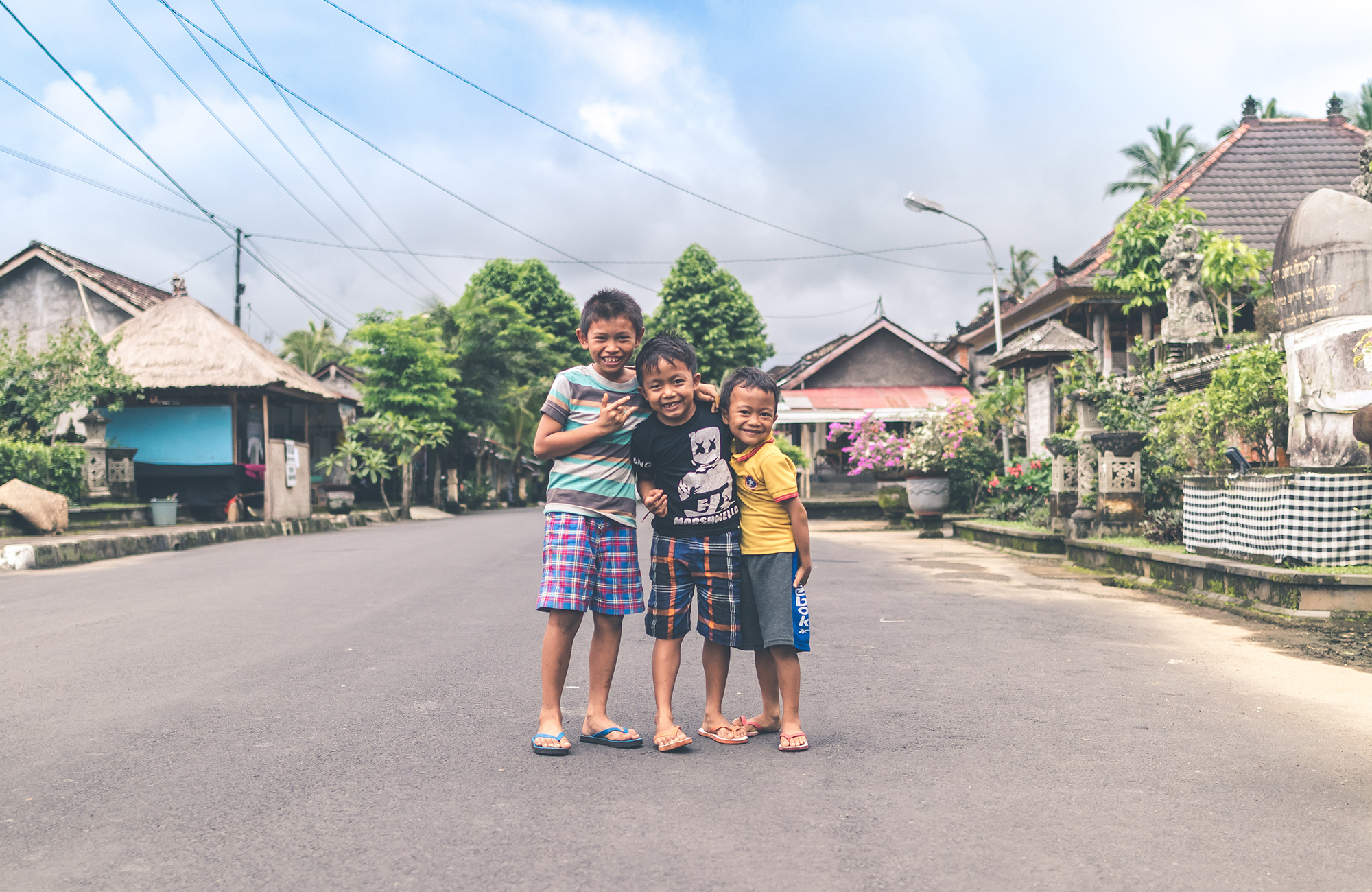 Image of three children posing for a photo on a street in Indonesia - KILROY