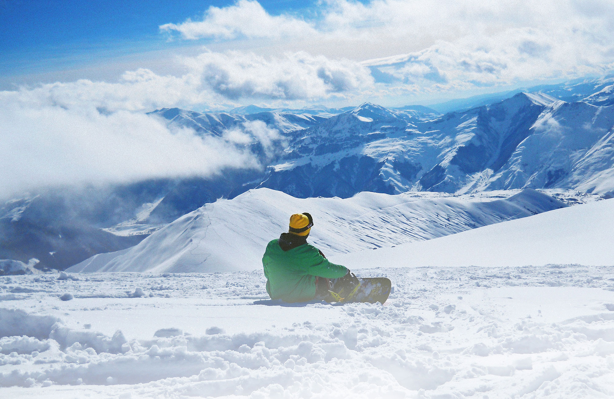 Image of a snowboarder looking out at a snowy mountain landscape in Canada - KILROY