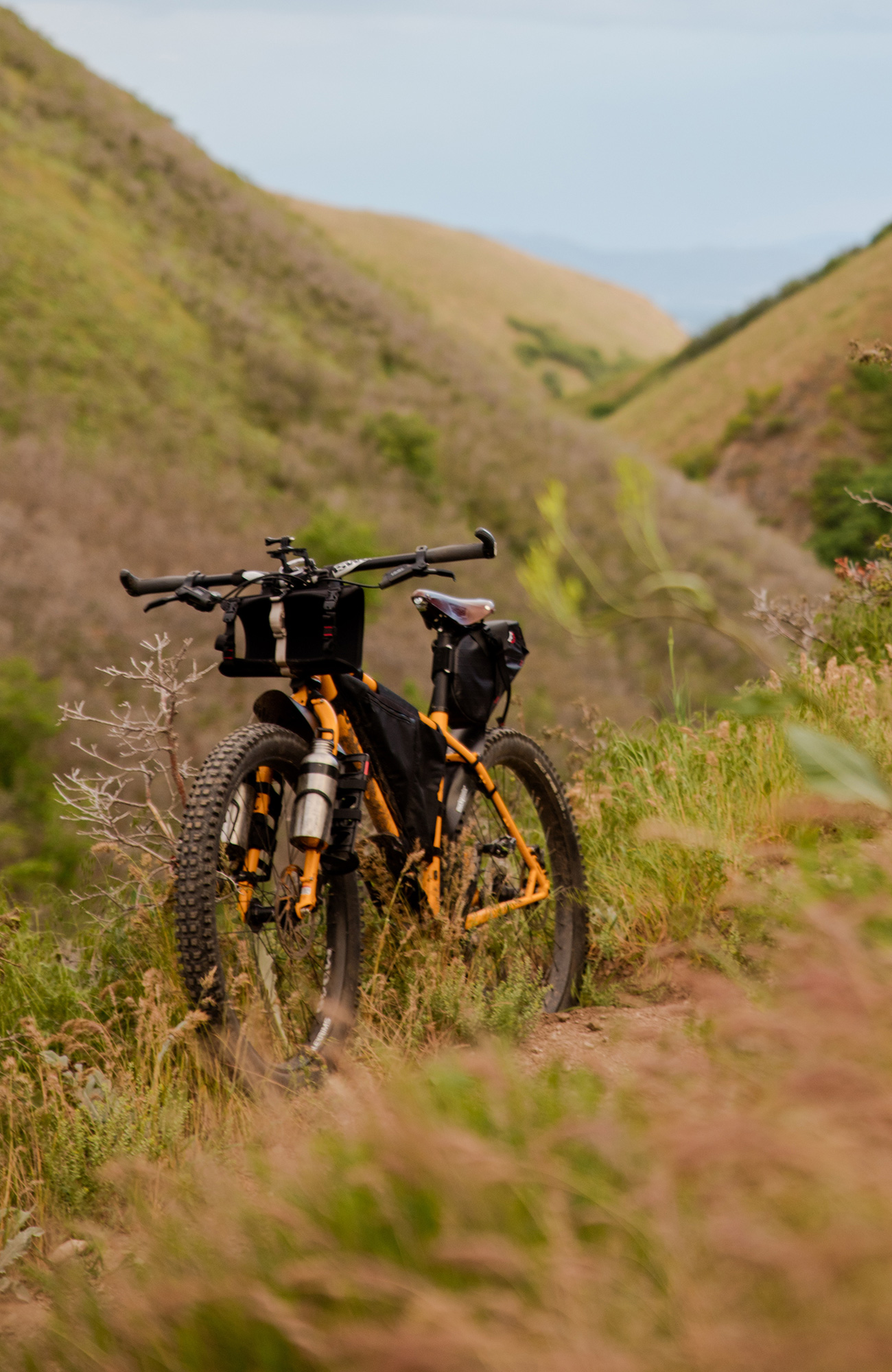 Image of a mountain bike resting with a backdrop of grassy hills - KILROY