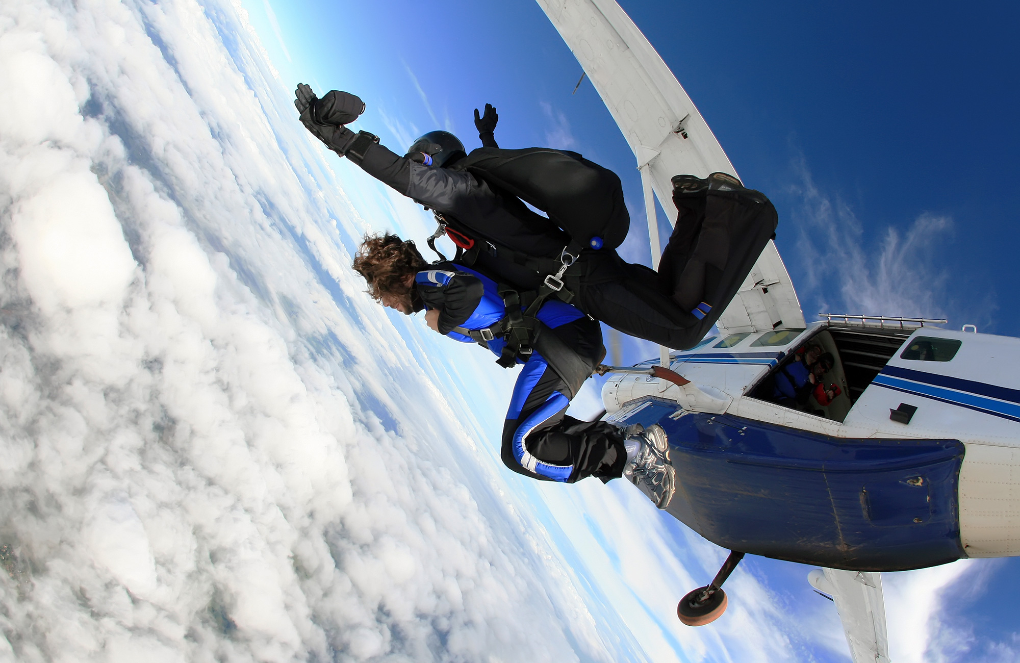 Image of a tandem skydive as two people jump out of a plane - KILROY