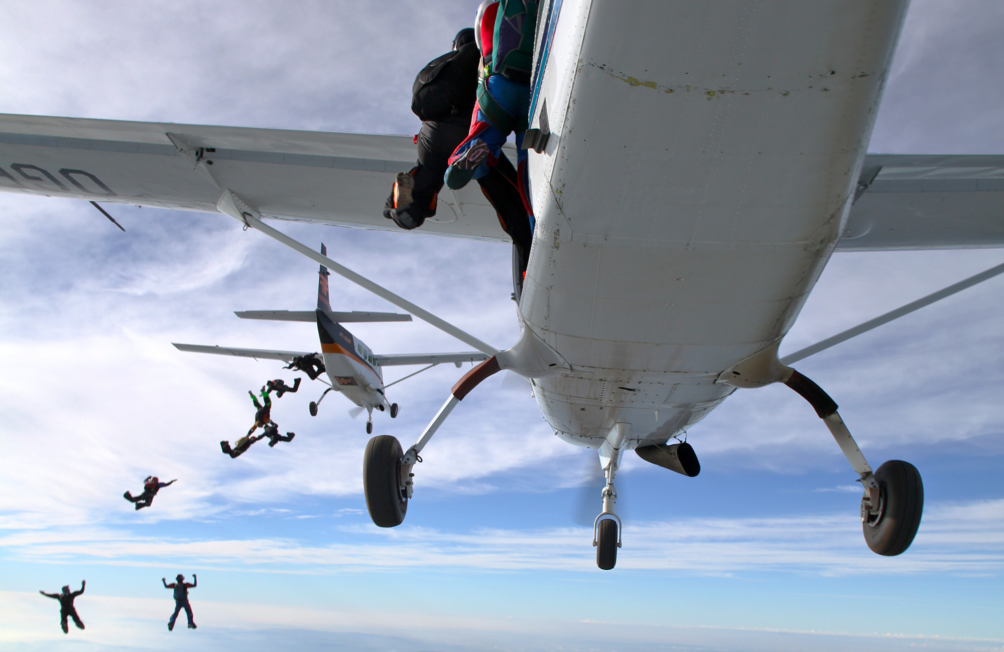 Image of a group of skydivers jumping out of a plane - KILROY