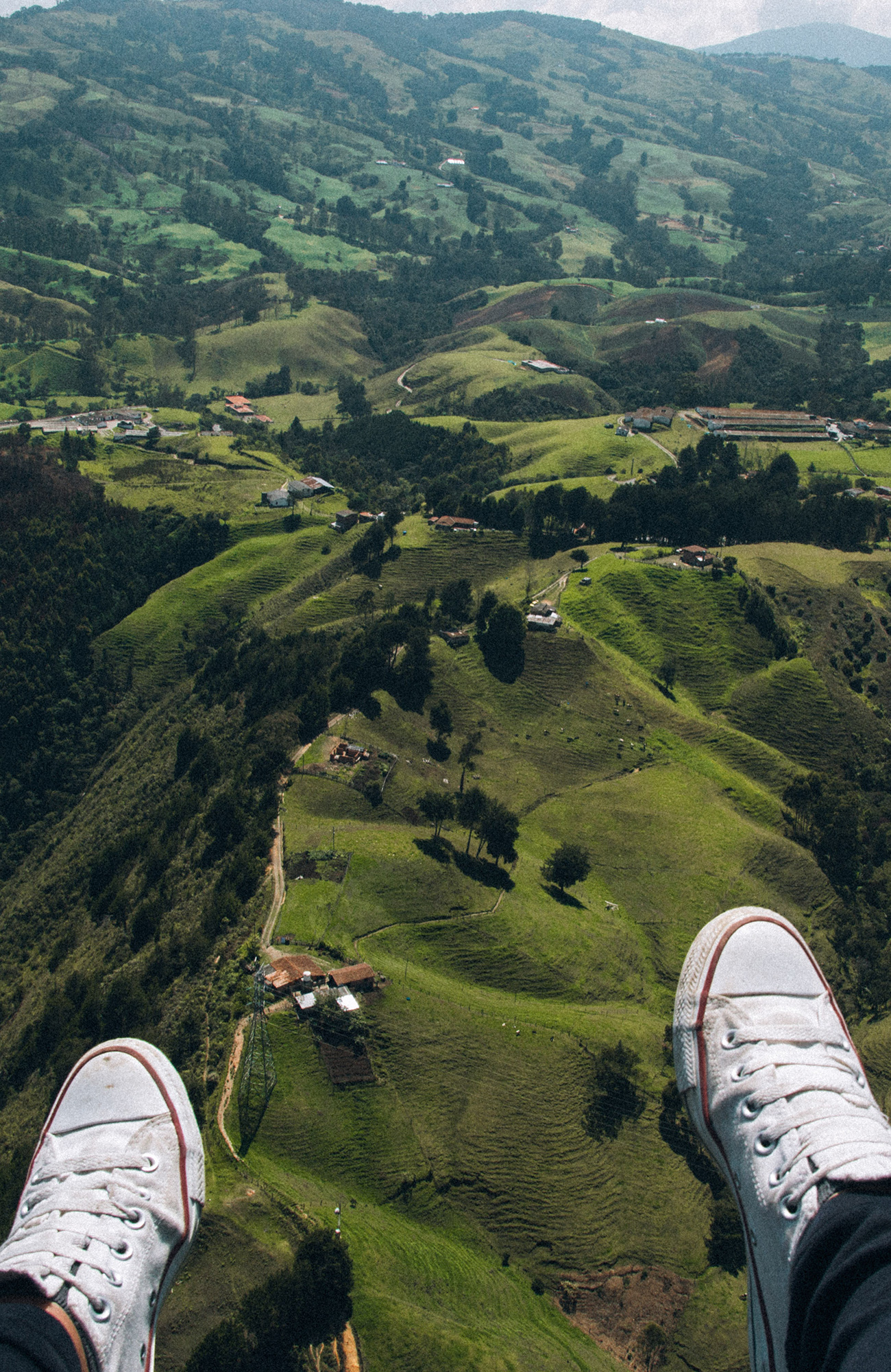 Image of a skydiver's feet as they soar above green hills below - KILROY