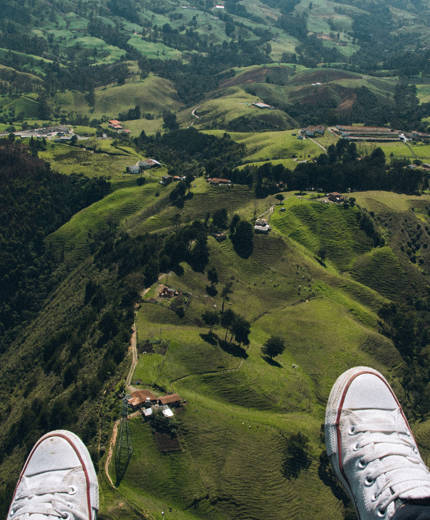 Image of a skydiver's feet as they soar above green hills below - KILROY
