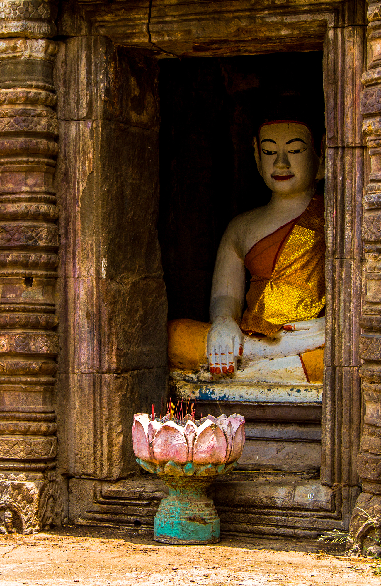 Image of a Buddhist statue seated in the window of an ancient temple in Cambodia - KILROY