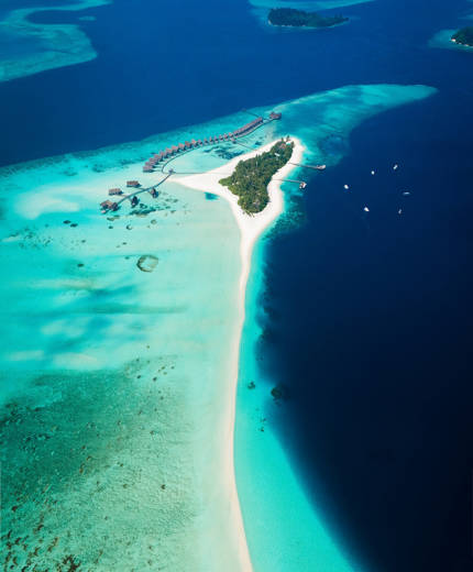 Aerial view of an island and its surrounding coral reefs in the Maldives - KILROY