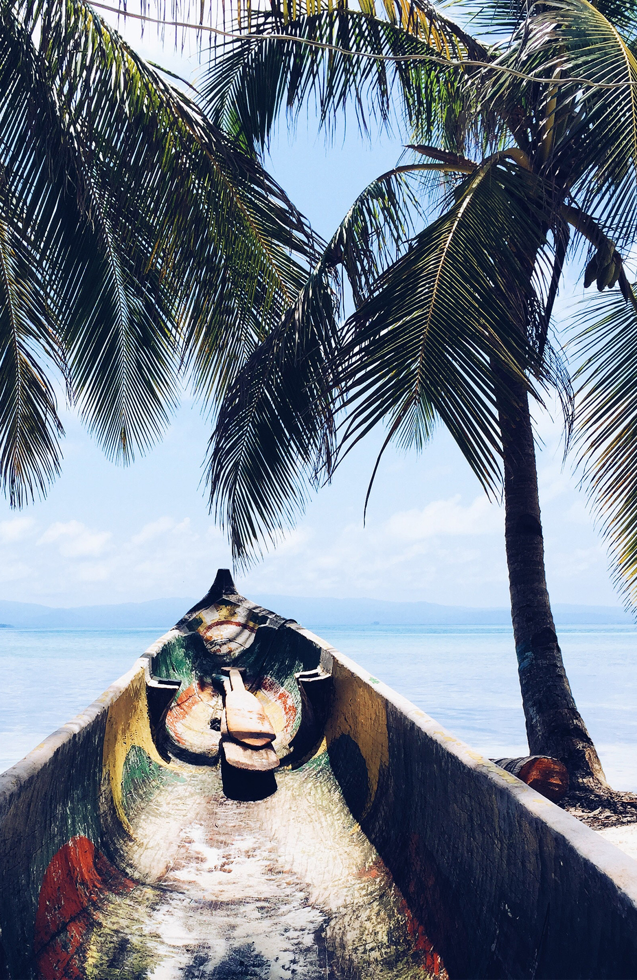 Image of a traditional wooden sailing boat sat on a beach next to a palm tree in Panama - KILROY