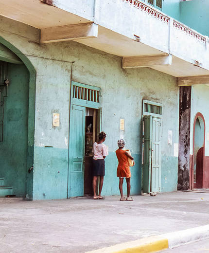 Image of two women standing outside of a faded painted house in Panama - KILROY