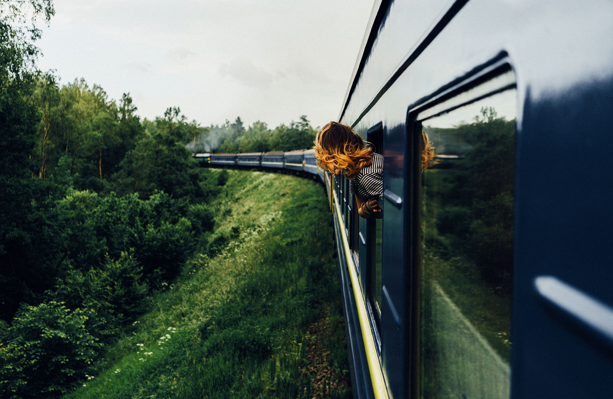 Image of a young woman looking out the window of a moving train -  KILROY