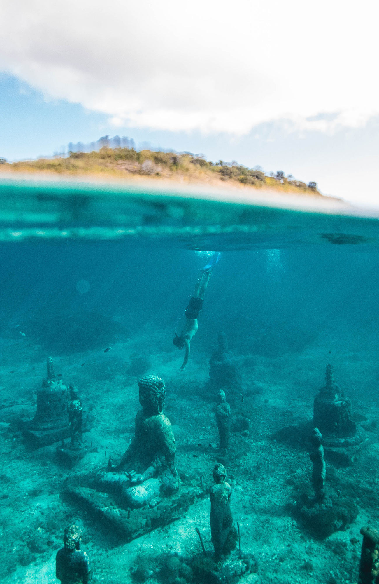 Image of a man diving under water with Buddhist temples littering the sea bed - KILROY