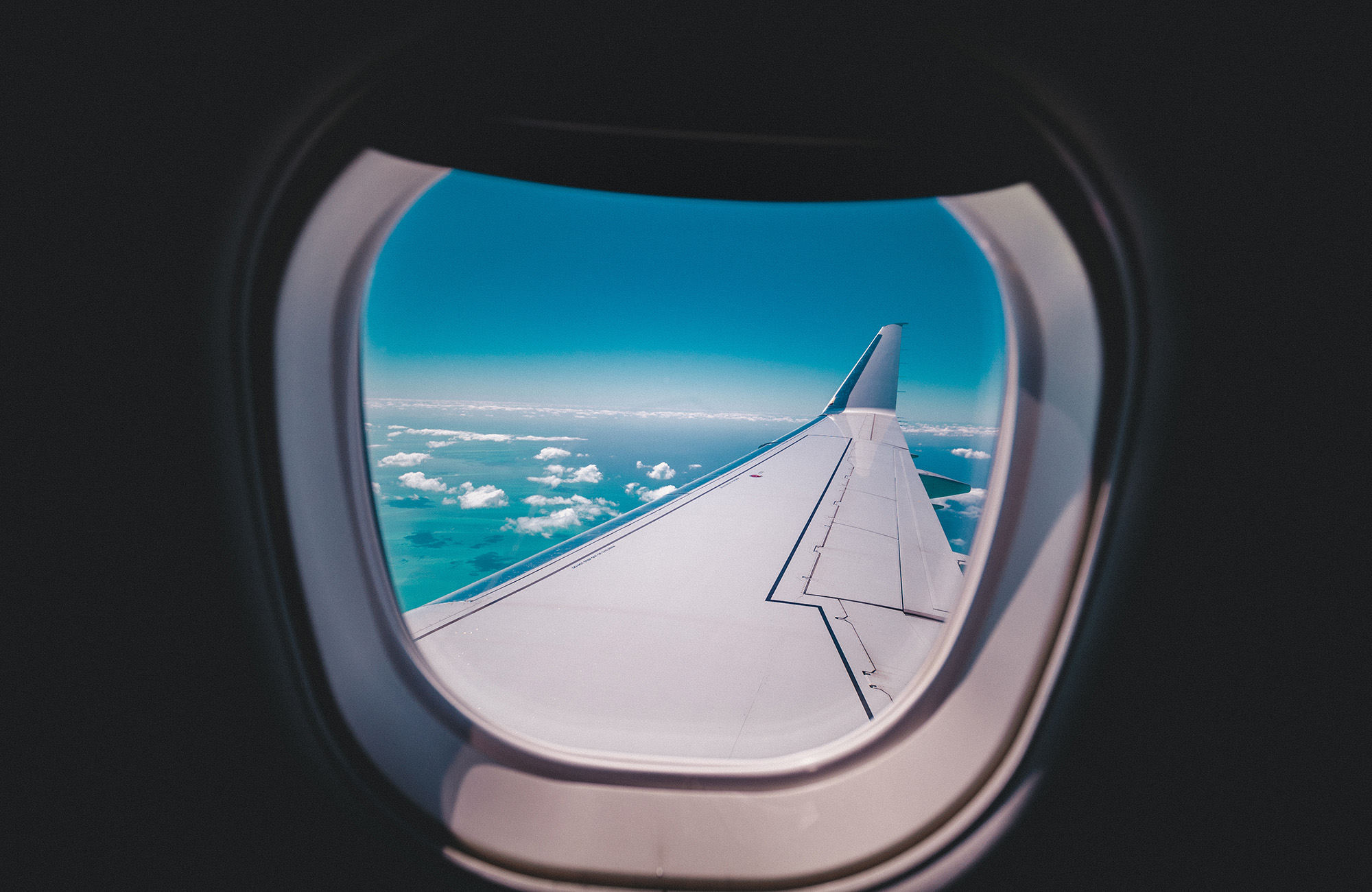 Image of a view out of an aeroplane window looking across the wing of the plane - KILROY