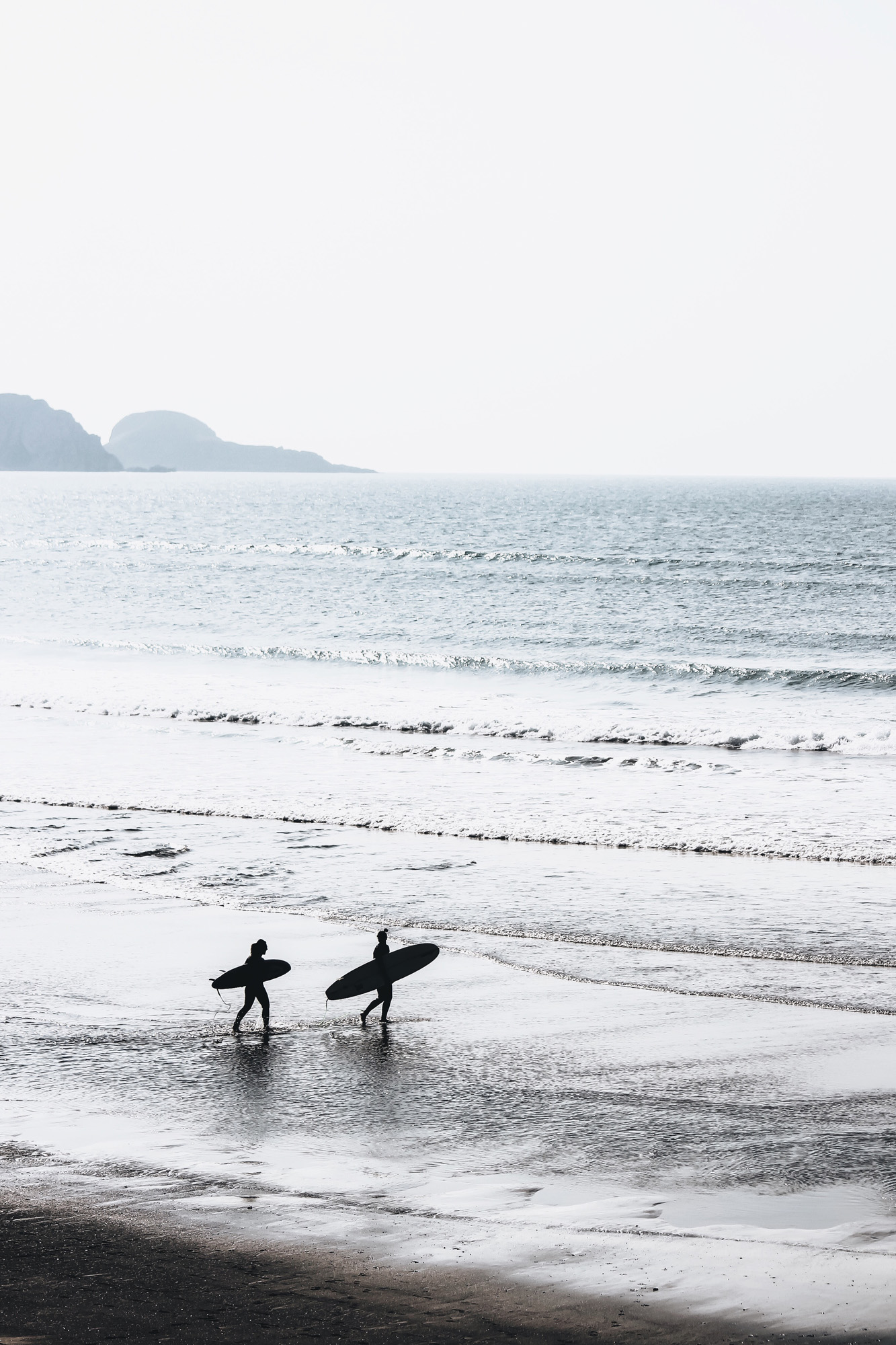 Image of the silhouettes of two surfers heading out to catch some waves - KILROY