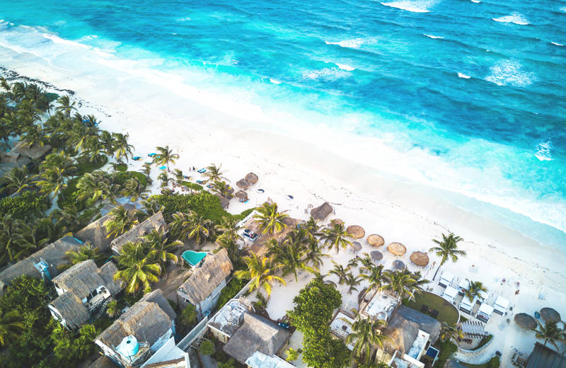 Aerial view of a beach backed by holiday resorts and palm trees in Tulum on the Caribbean coast of Mexico - KILROY