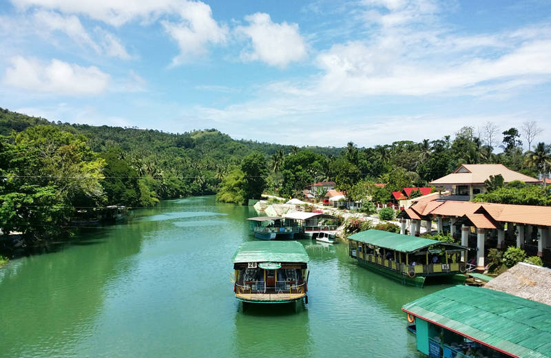 Wide boats with a green roof on a river on Cebu island