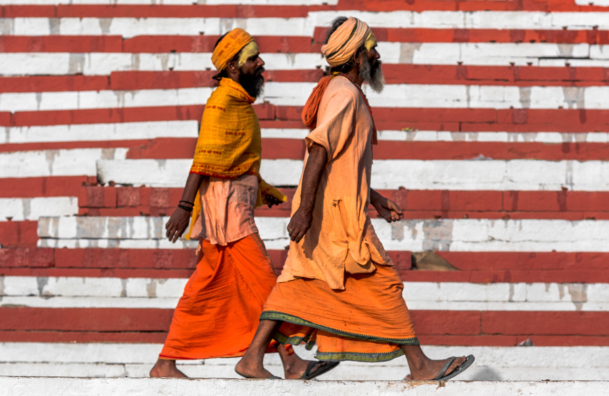 Image of two sadhus walking against a colourful background in India - KILROY