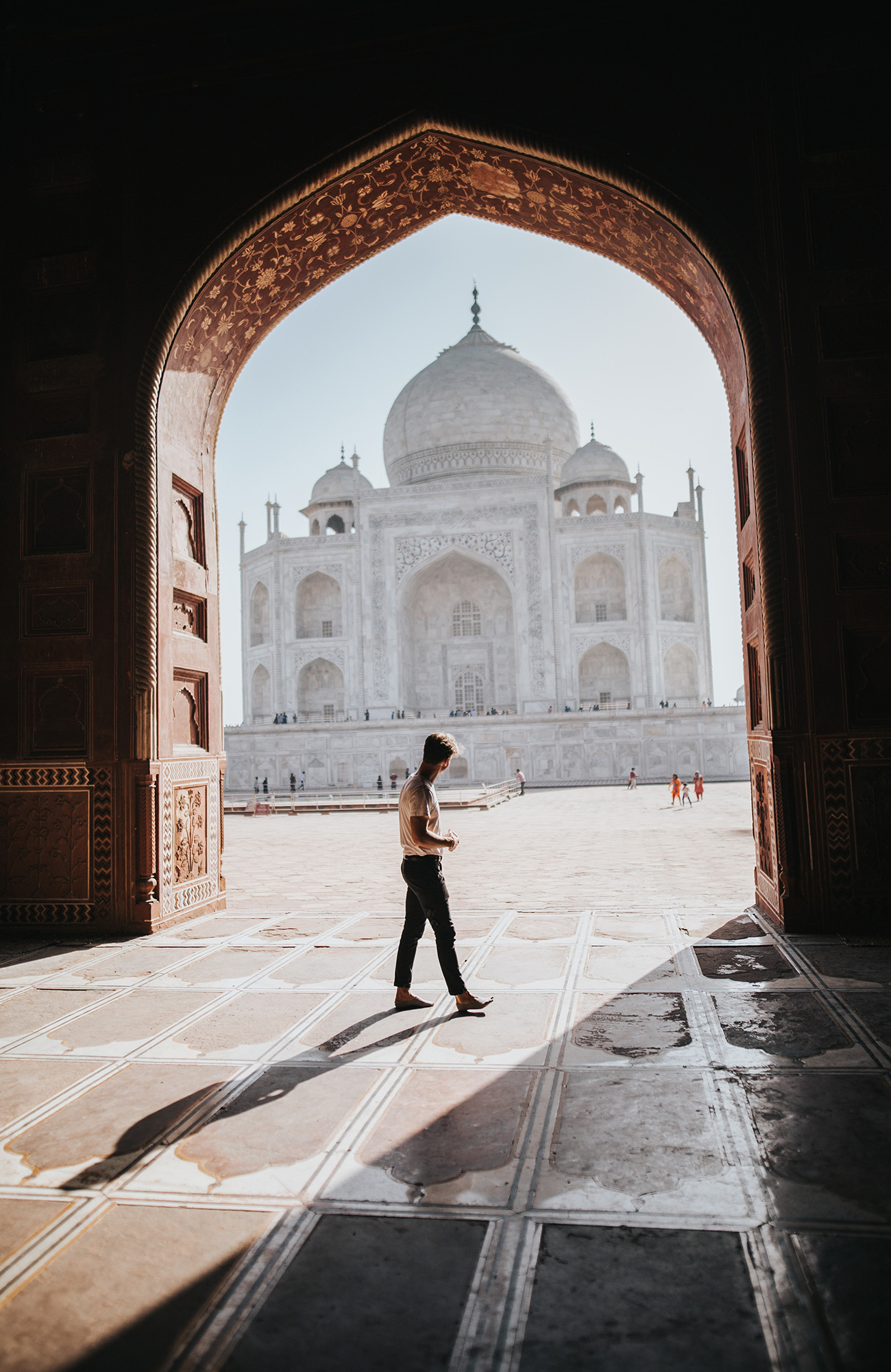 Image of a traveller walking near a doorway looking out towards the Taj Mahal in India - KILROY