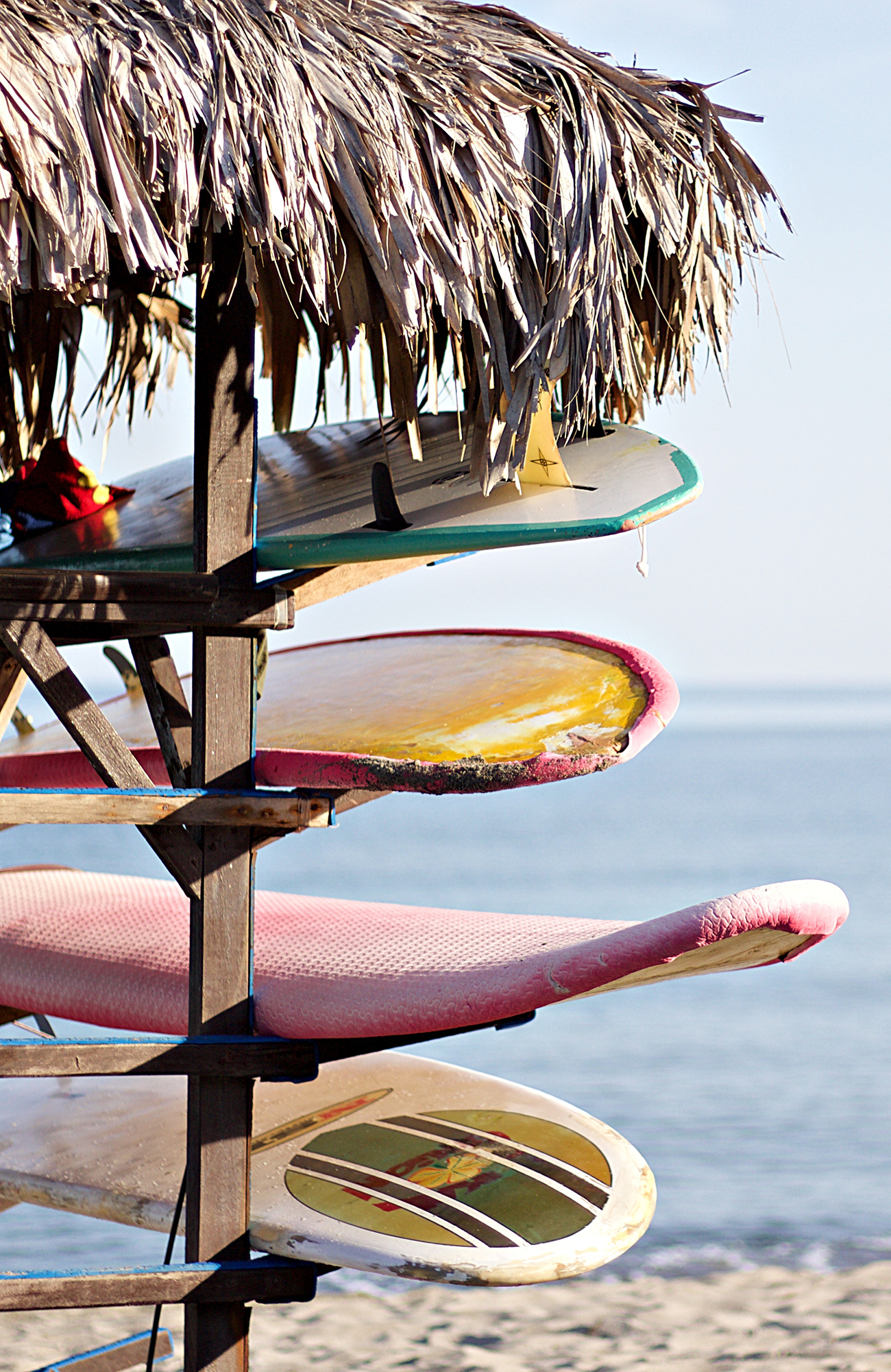 Image of surfboards stacked up on a beach in Portugal - KILROY