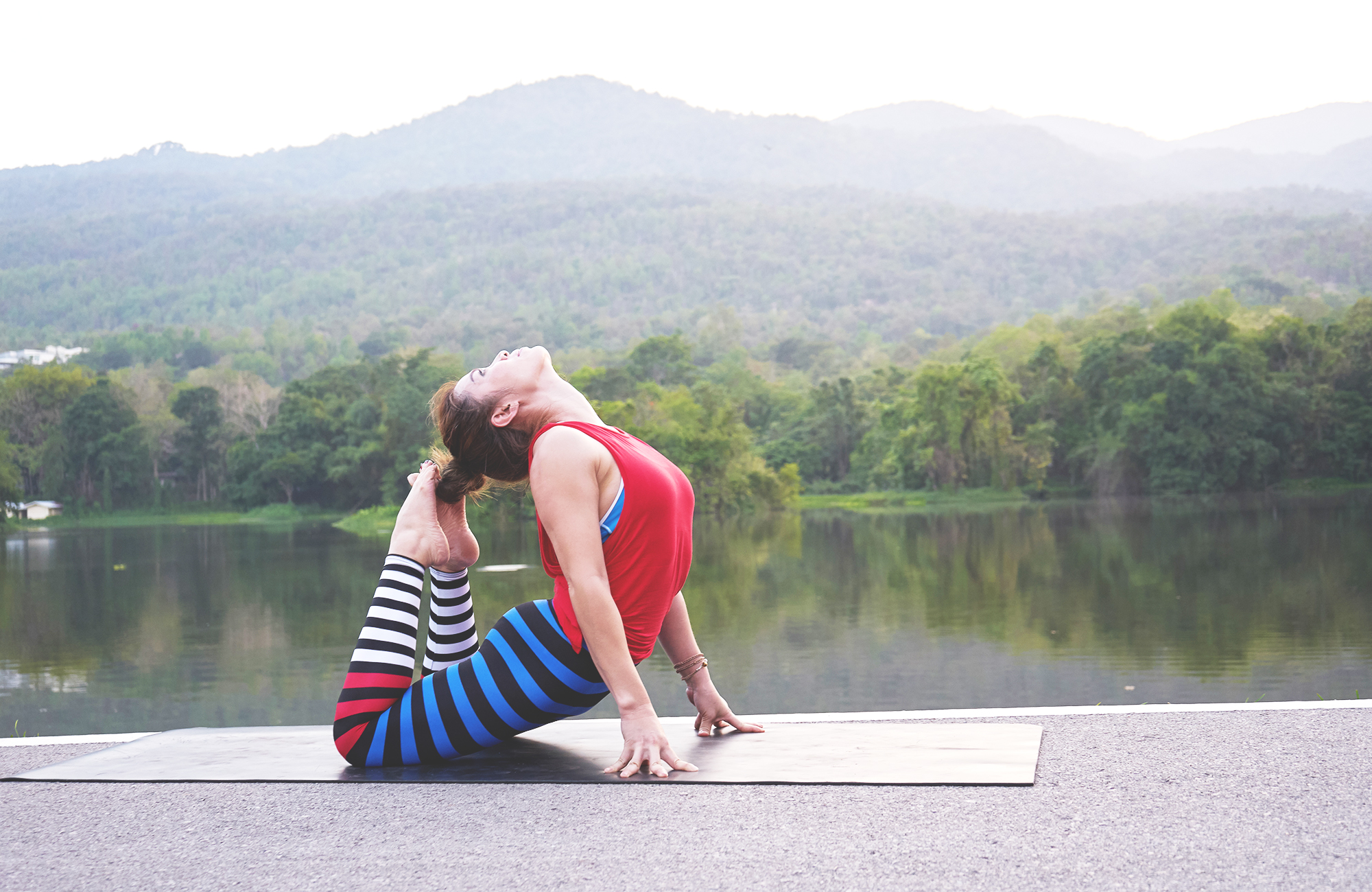 Image of a woman in a yoga pose near a lake - KILROY