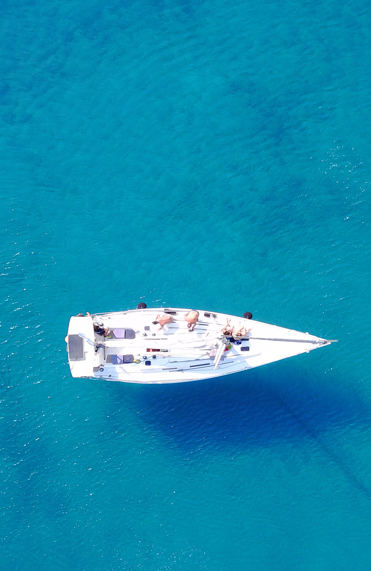 Aerial view of a sail boat on calm blue waters - KILROY