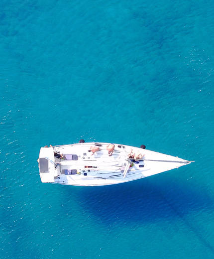 Aerial view of a sail boat on calm blue waters - KILROY
