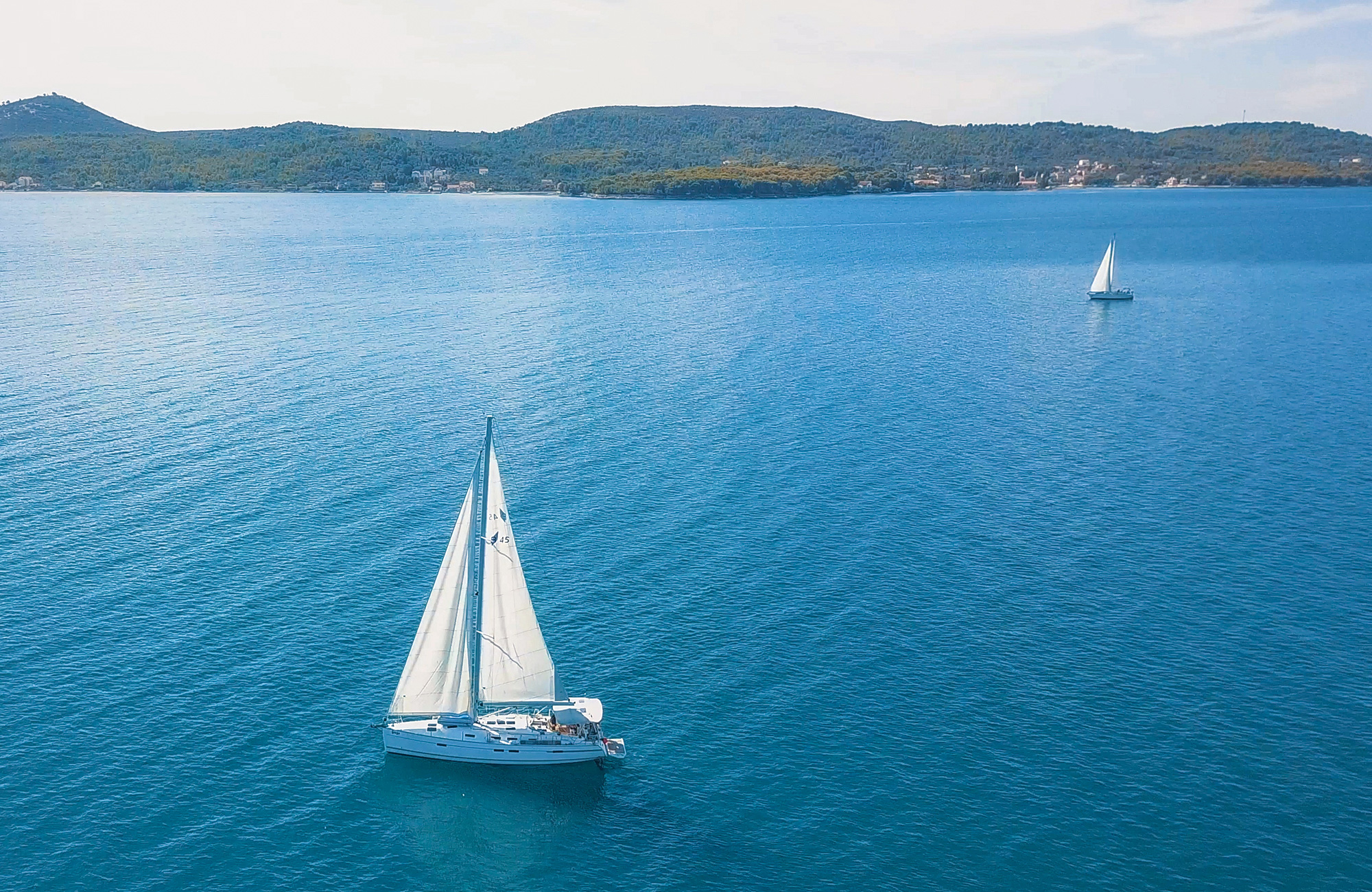 Image of two sail boats on a calm blue sea in Oceania - KILROY