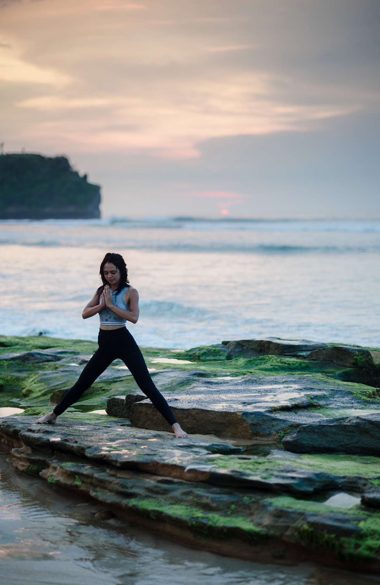 Image of a woman practising yoga on a rocky outcrop near the ocean - KILROY