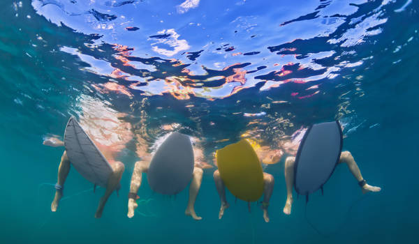surfing-surfers-sitting-on-boards-underwater-cover