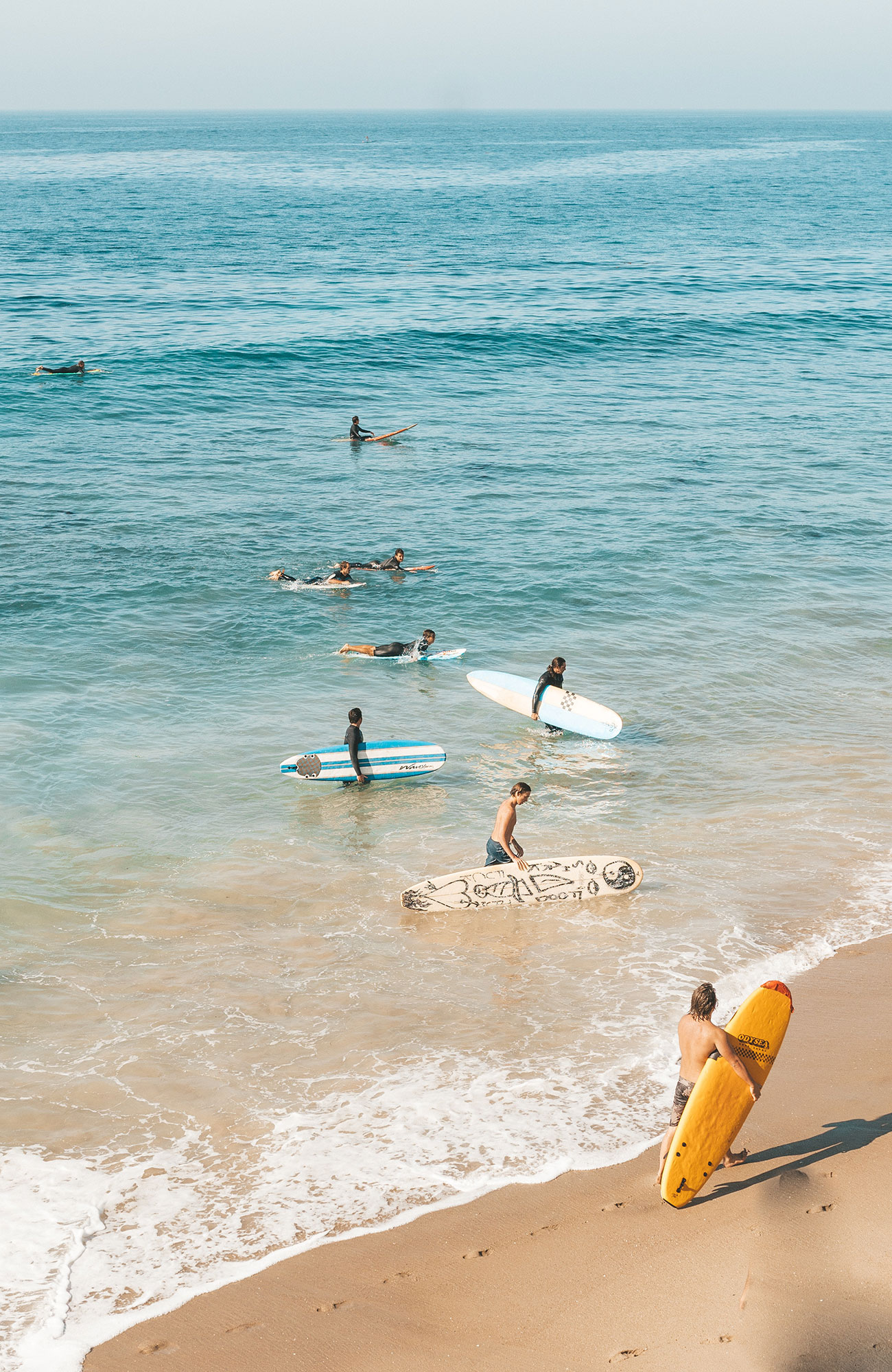 Image of surfers in the water near a beach in Europe - KILROY