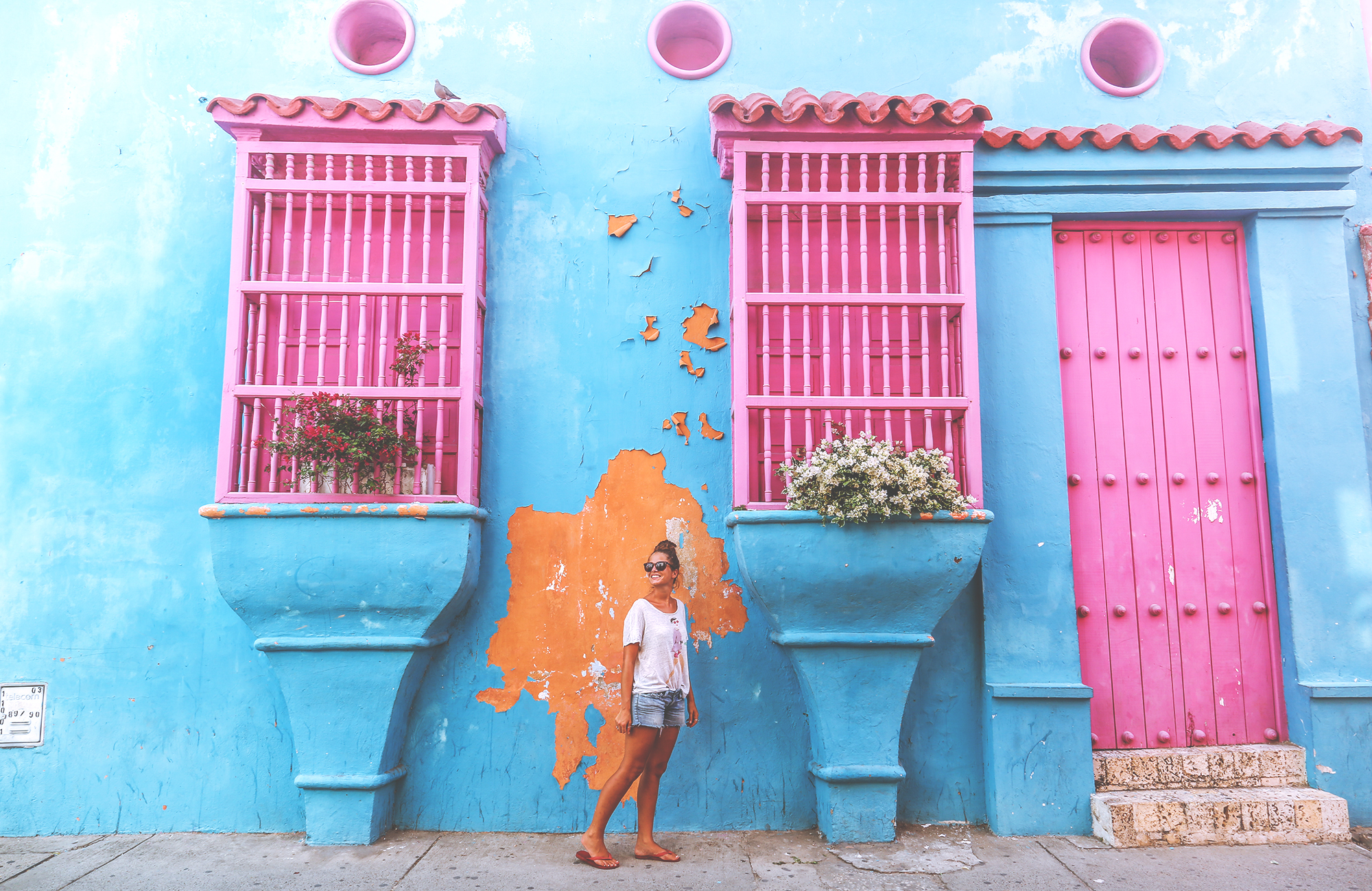 Image of a female traveller in front of a colourful building facade in Cartagena - KILROY