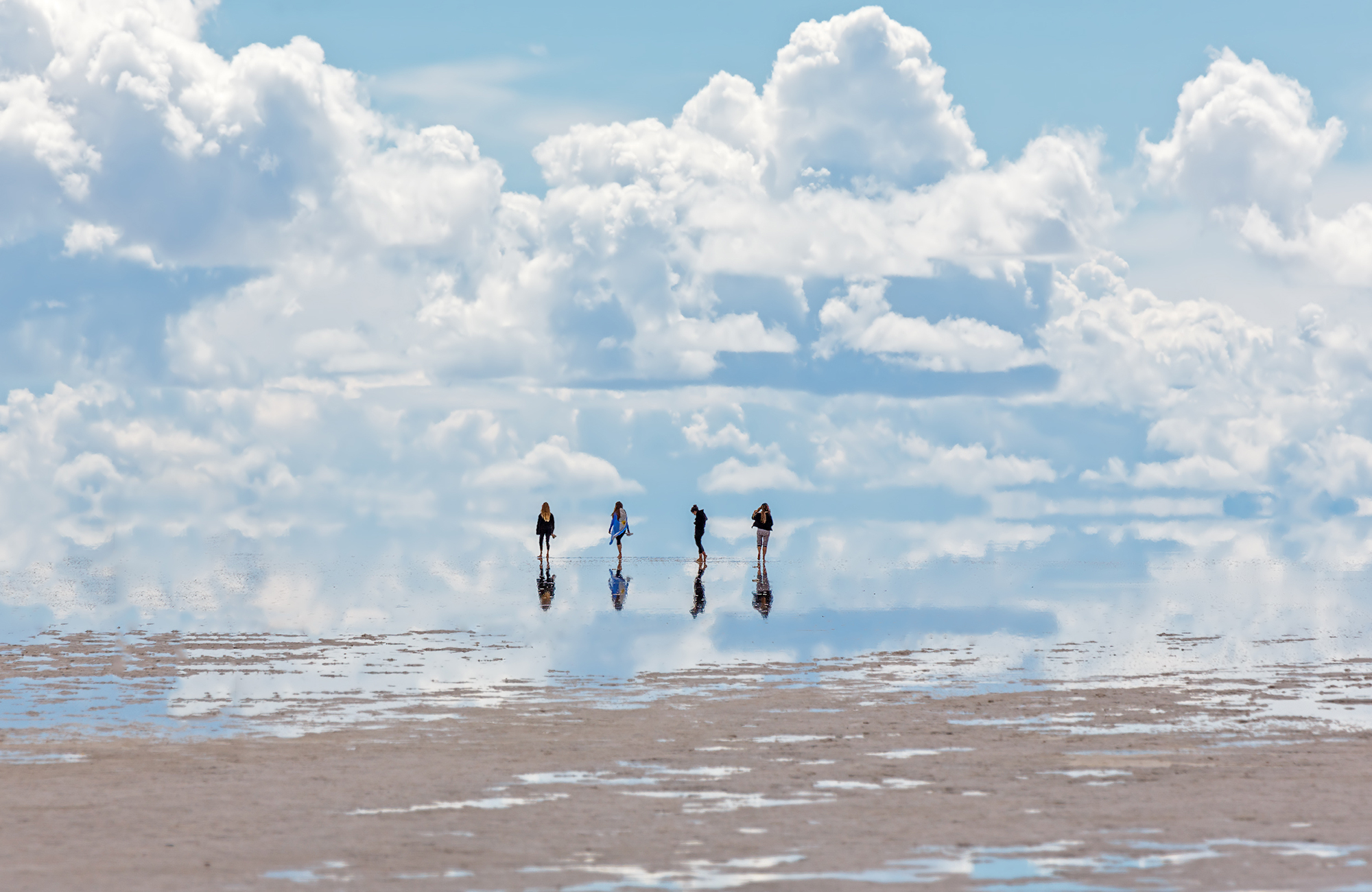 A group of people on an adventure tour visiting the Uyuni salt flats in South America - KILROY