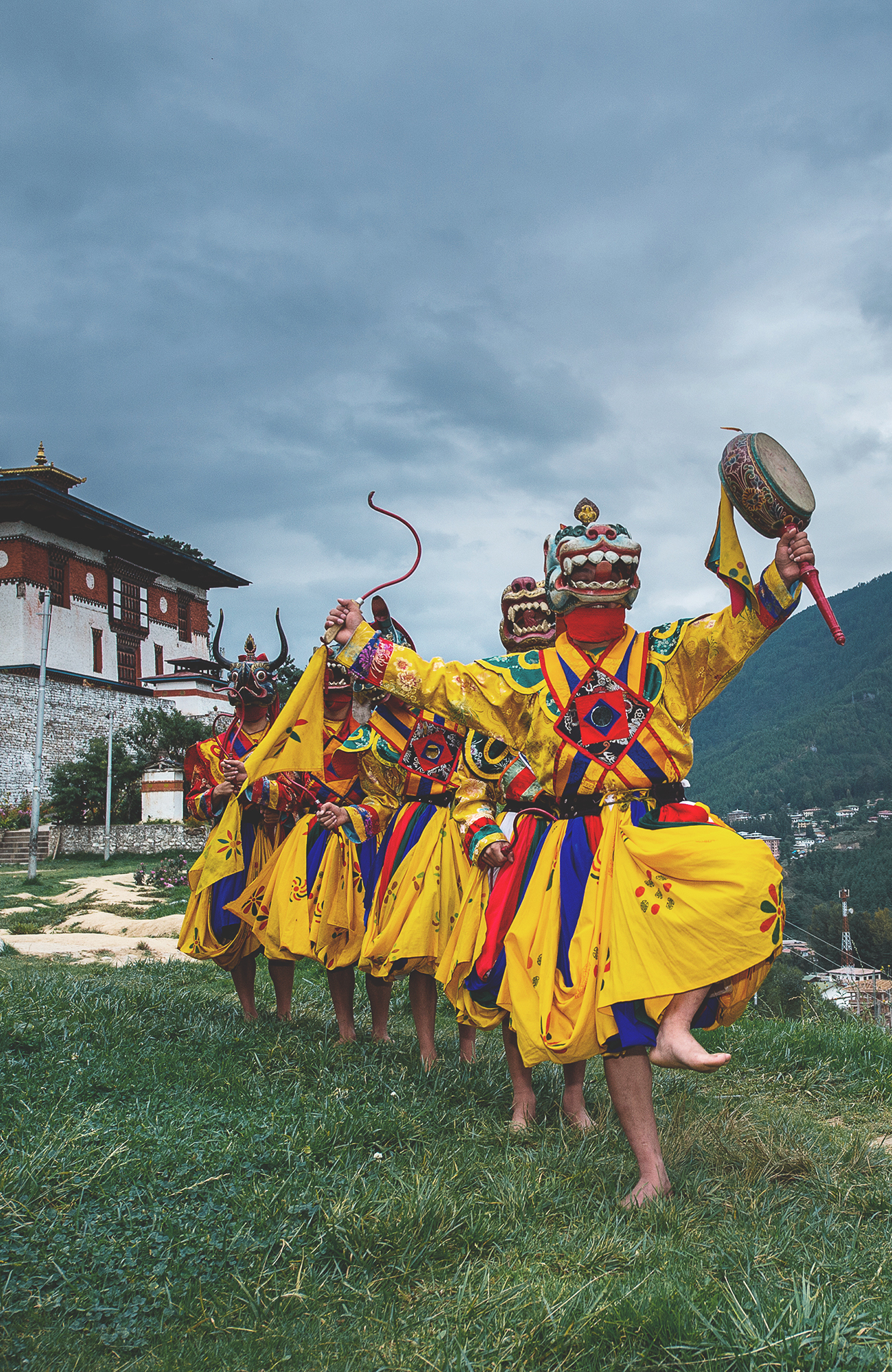 Image of masked dancers in colourful robes performing at a festival in Bhutan - KILROY