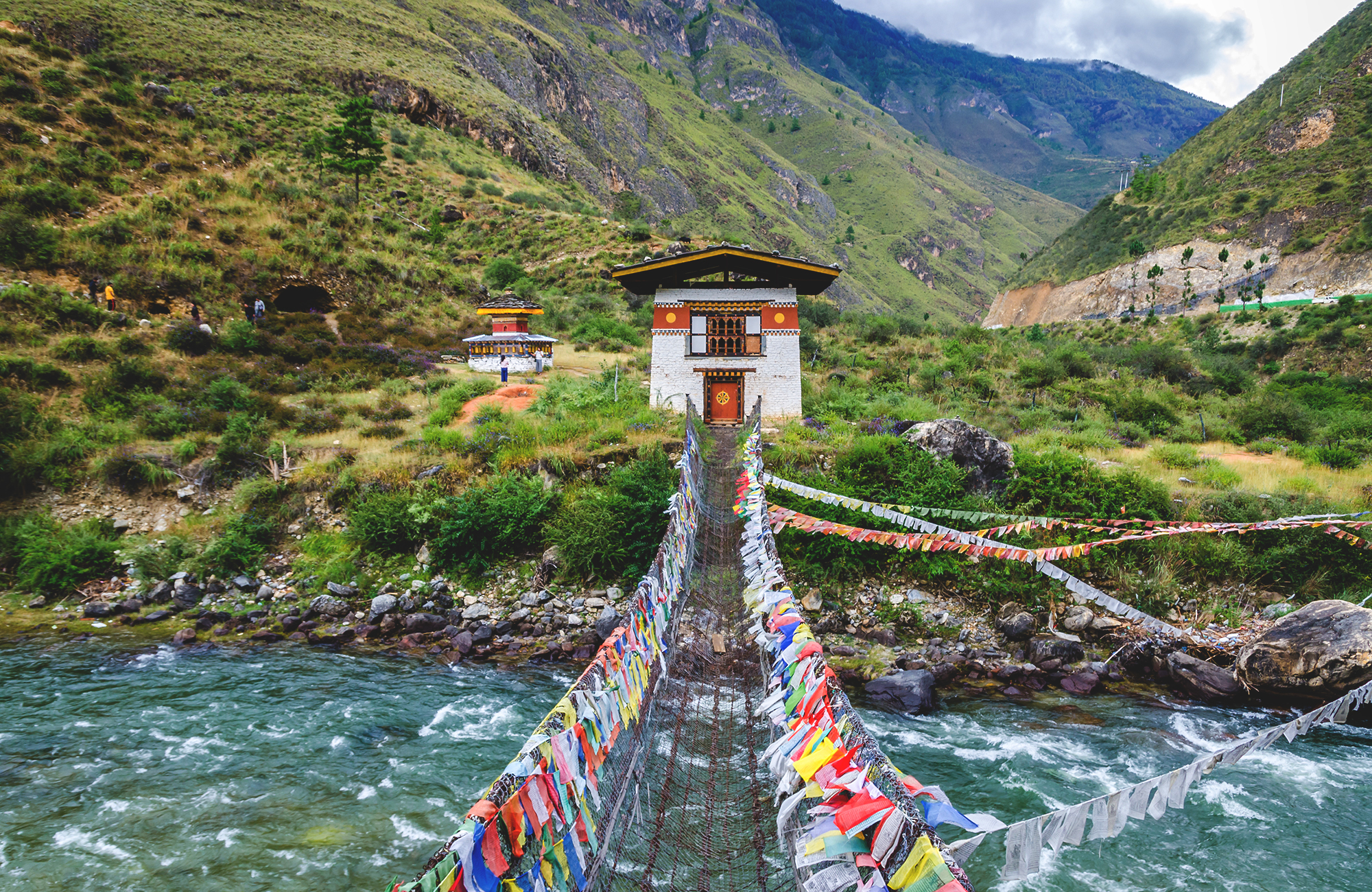 Image of a bridge across a river in a valley in Bhutan - KILROY