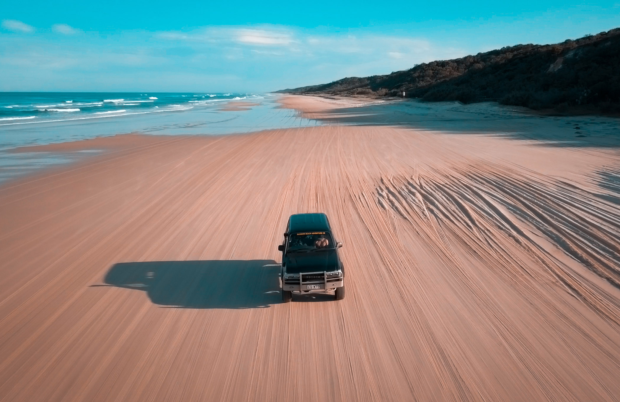 Image of a 4x4 driving across the sandy beach of K'gari in Australia - KILROY