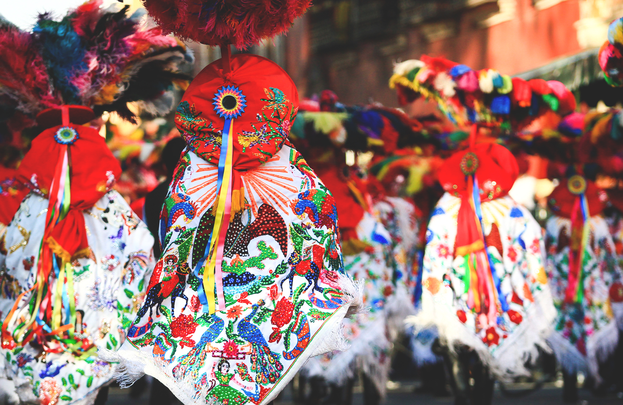 Image of a parade of people wearing colourful costume in Mexico - KILROY