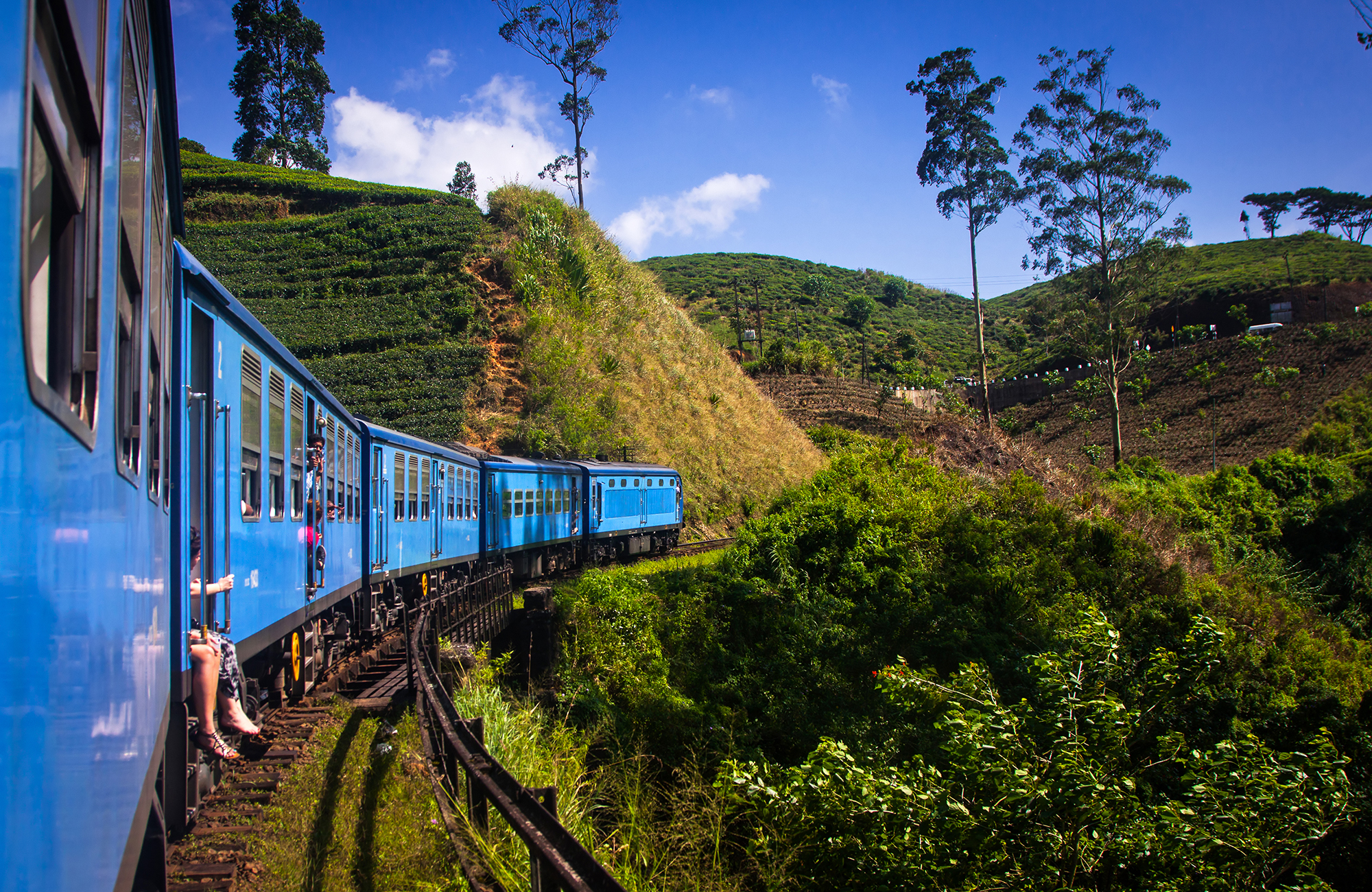 Image of the iconic blue train riding the tracks near Ella in Sri Lanka - KILROY