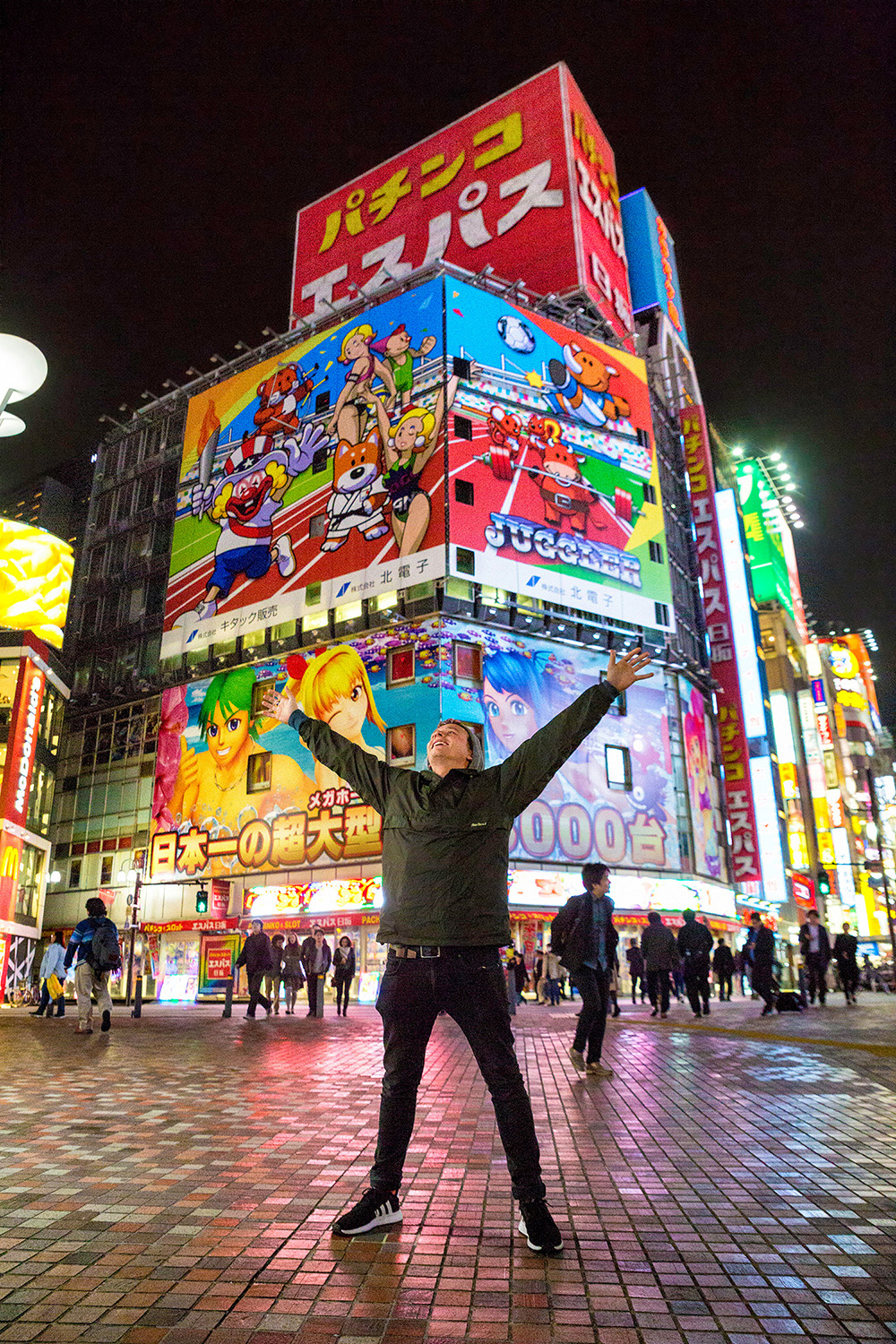 Image of a young male traveller posing in front of neon billboards in Tokyo - KILROY