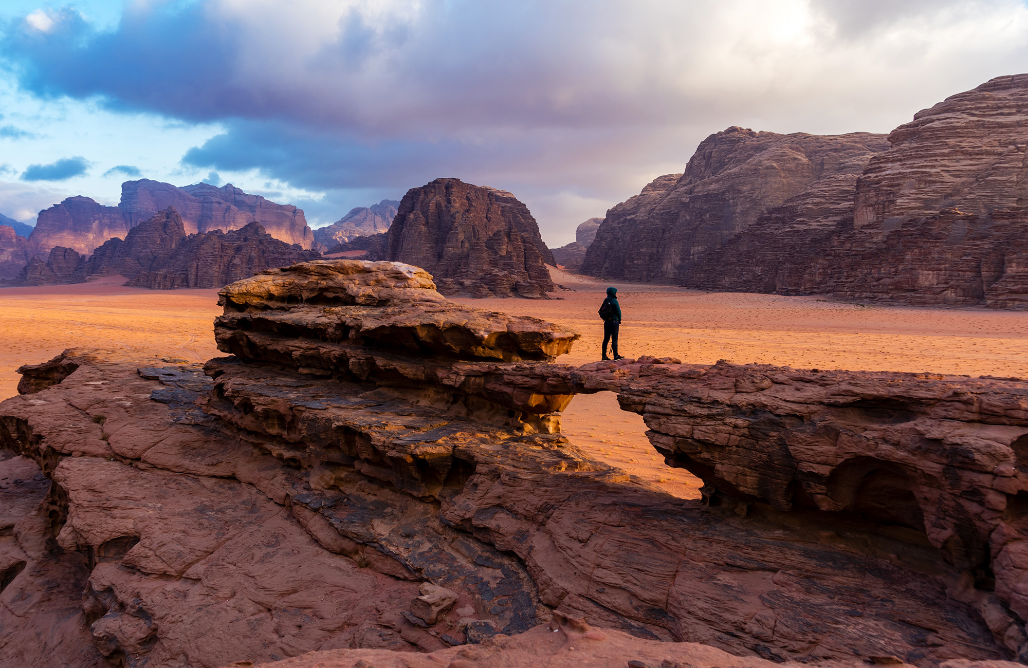 Image of a traveller standing on a rock formation in Wadi Rum, Jordan - KILROY