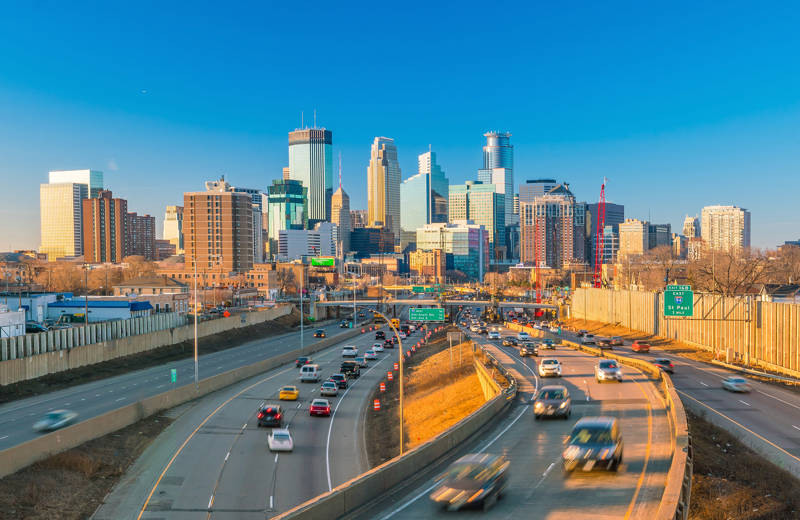 Busy highways into Minneapolis, with the skyline of the city against a bright blue sky