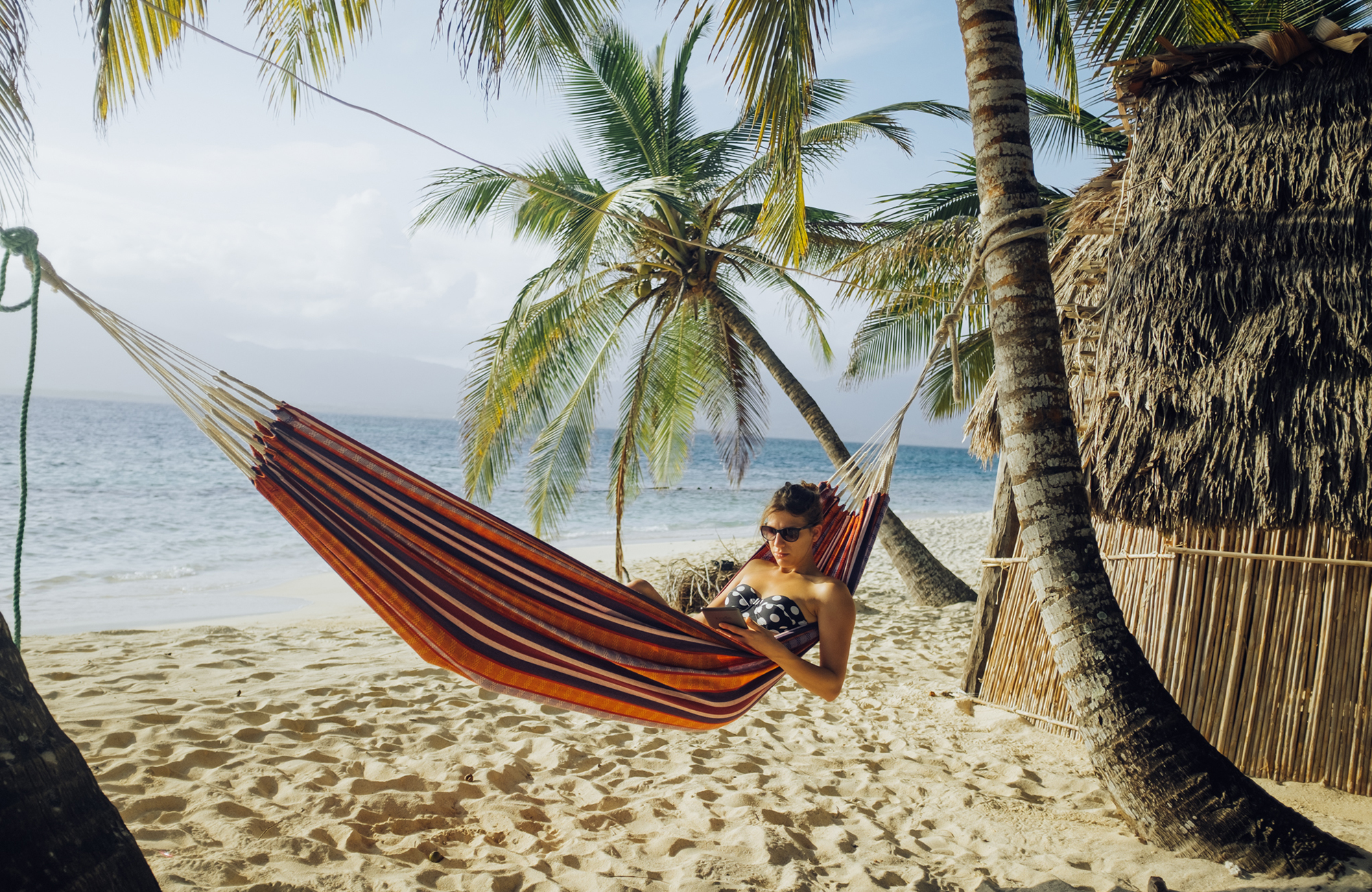 Woman studying Spanish in a hammock on a tropical beach in Central America