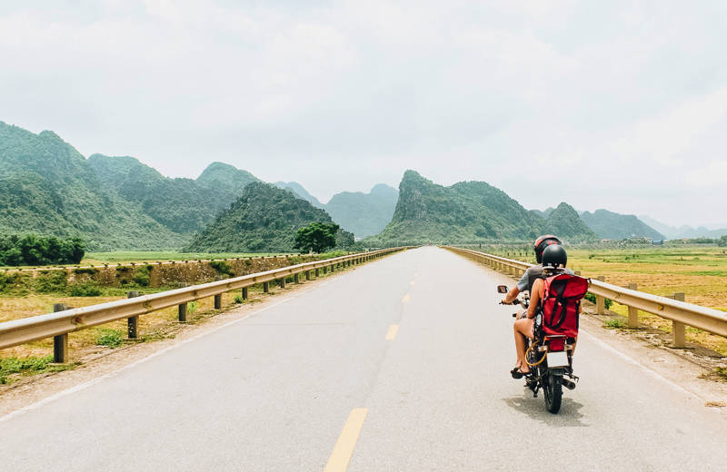 Travellers on a motorbike on an empty road in Vietnam