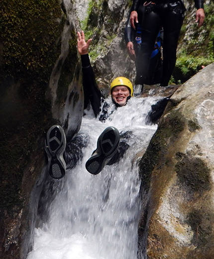 Image of a man in a narrow river surrounded by boulders - KILROY