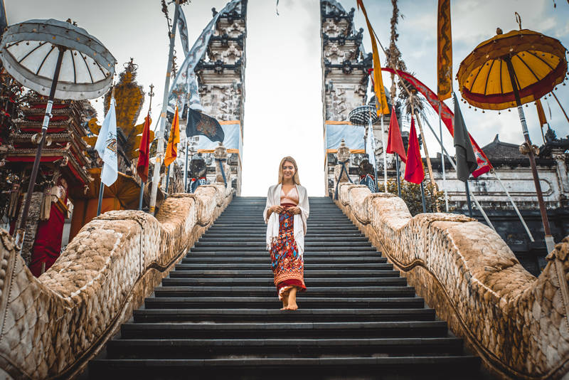 Image of a female traveller walking down the steps of a temple in Bali, Indonesia - KILROY