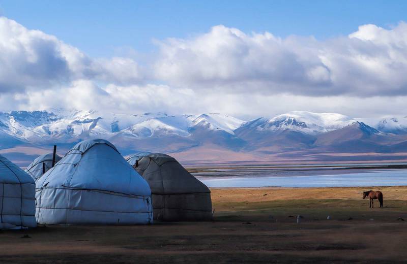 Image of traditional yurts with a lake and mountains in the background of Kyrgyzstan - KILROY