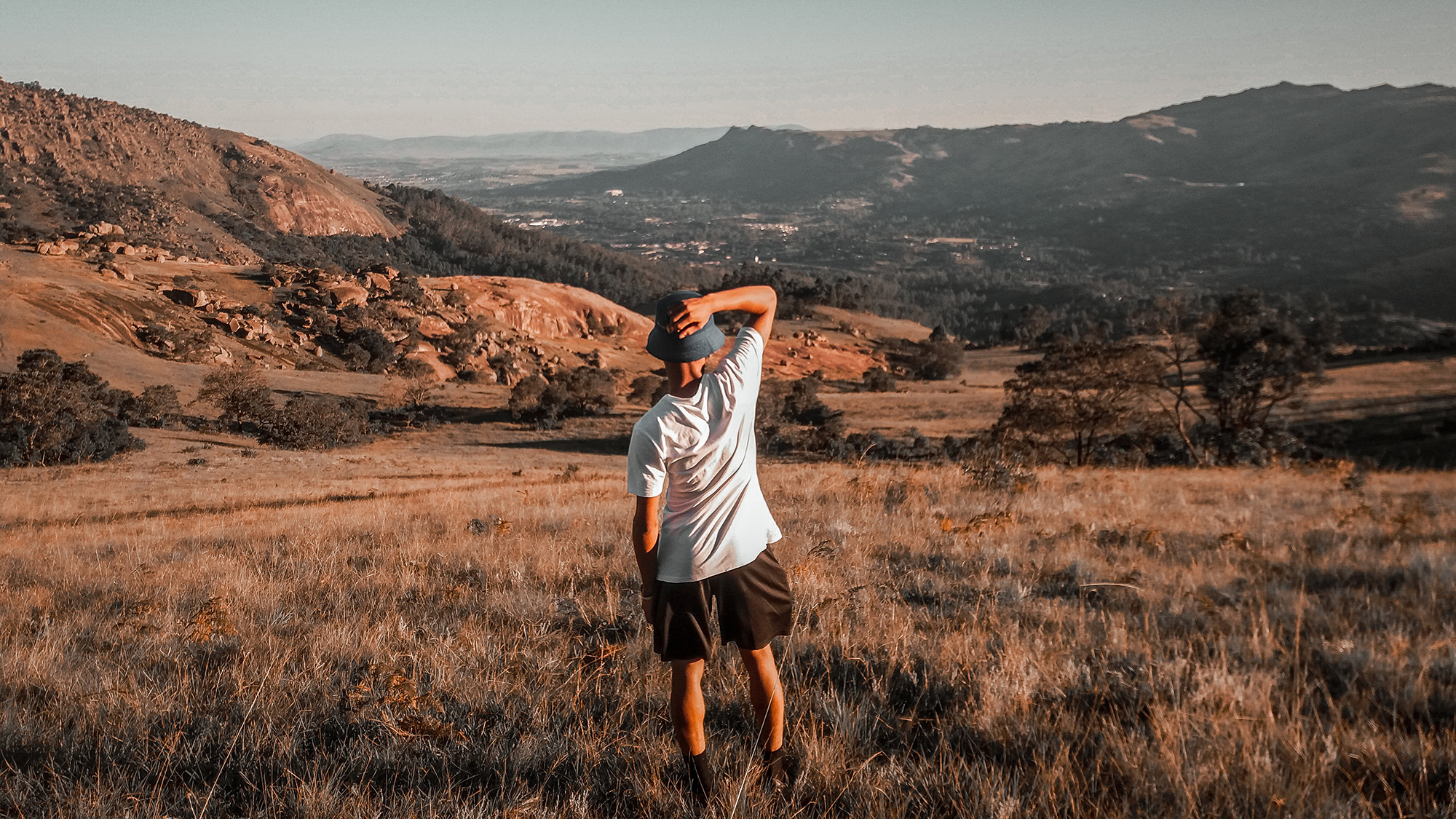 Guy standing in a field in Eswatini, looking at the mountainous view