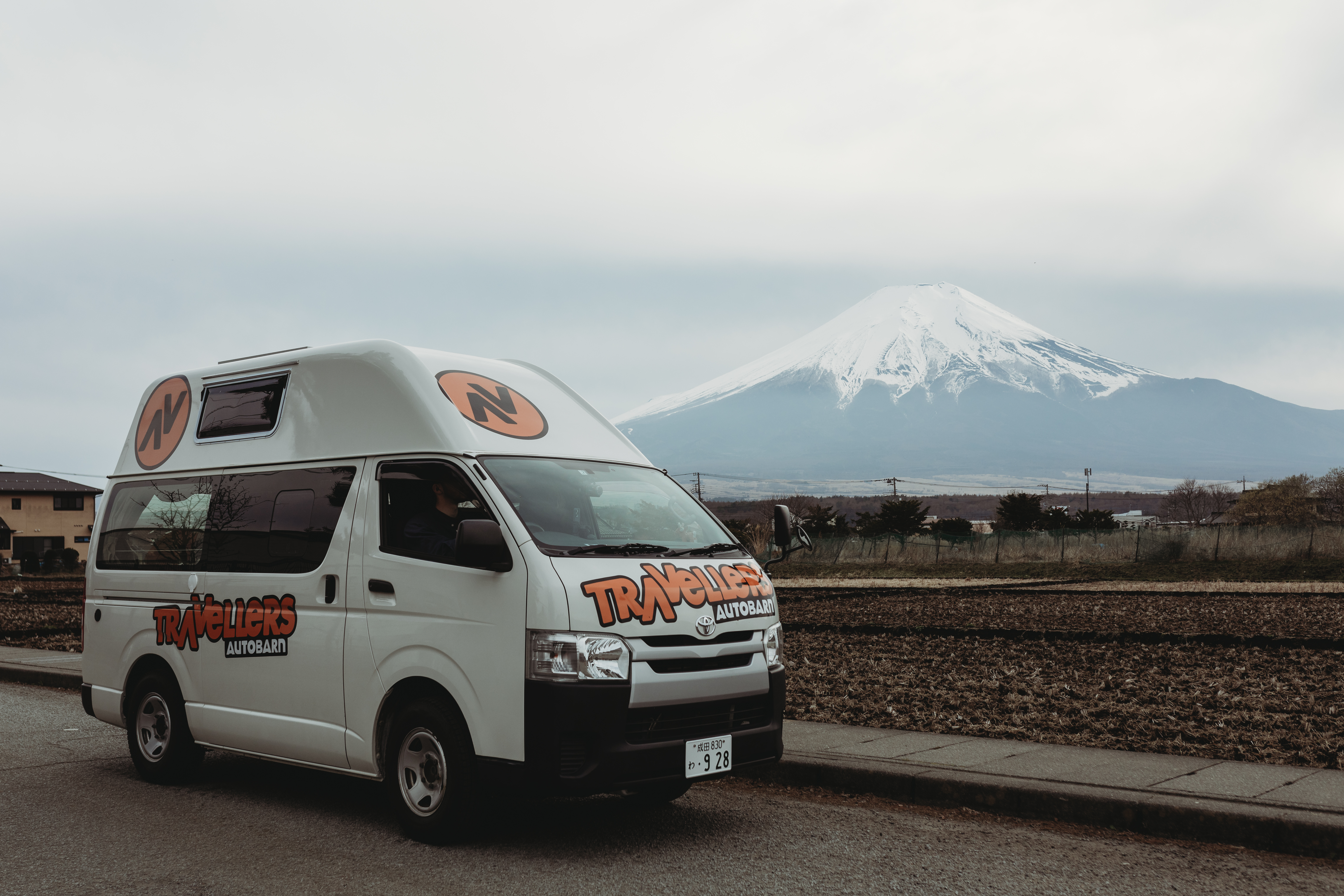 Image of a campervan parked on a road with Mt. Fuji in the background - KILROY