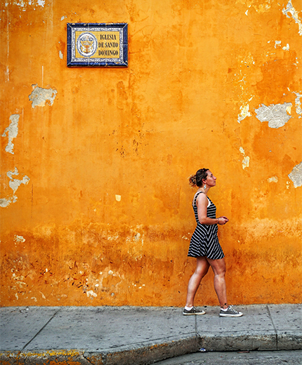 Image of a woman walking along a colourful street in Cartagena in the north of Colombia along the Caribbean coast - KILROY